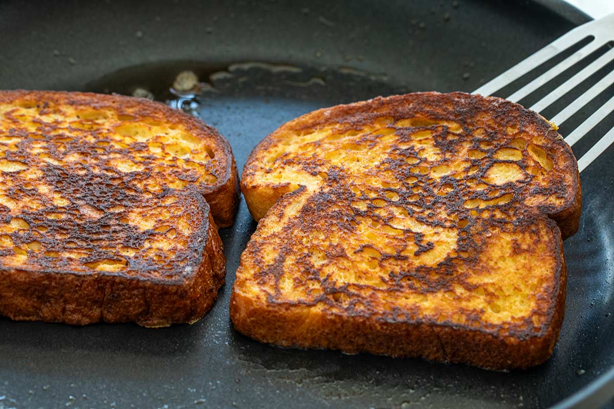 Slices of bread frying in a pan with butter.