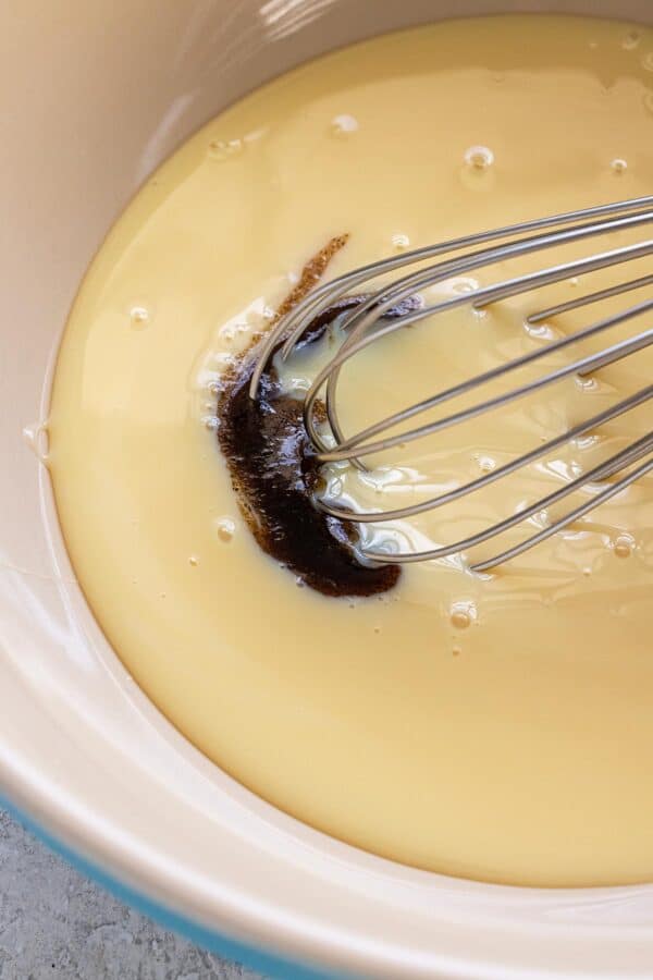 Vanilla being incorporated into a bowl of sweetened condensed milk.