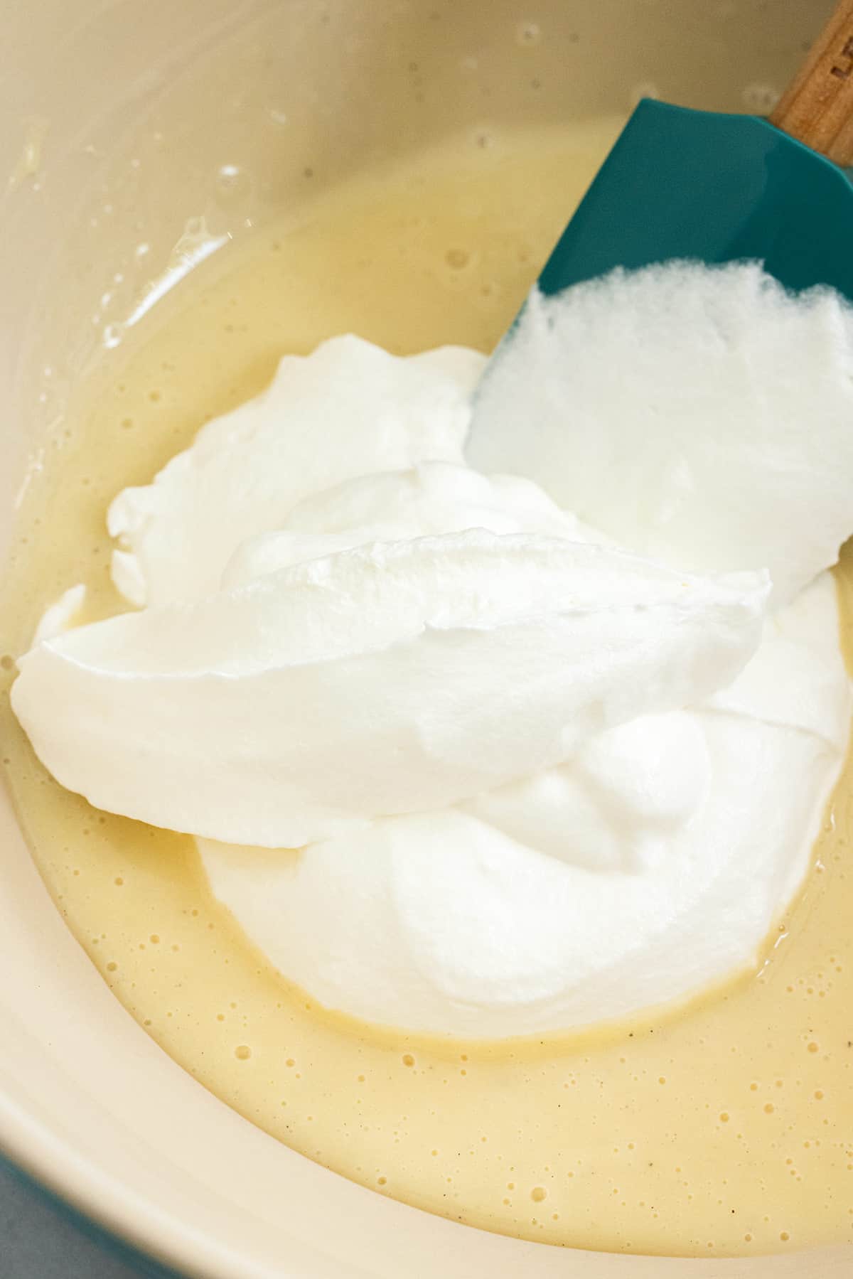 Homemade whipped cream added to a bowl of sweetened condensed milk.