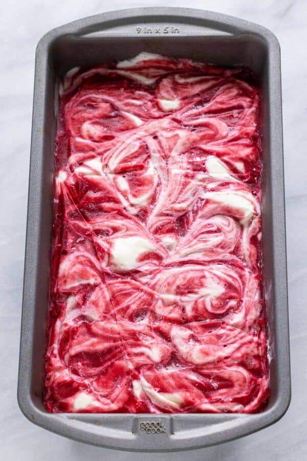 Frozen raspberry swirl ice cream in a metal pan.