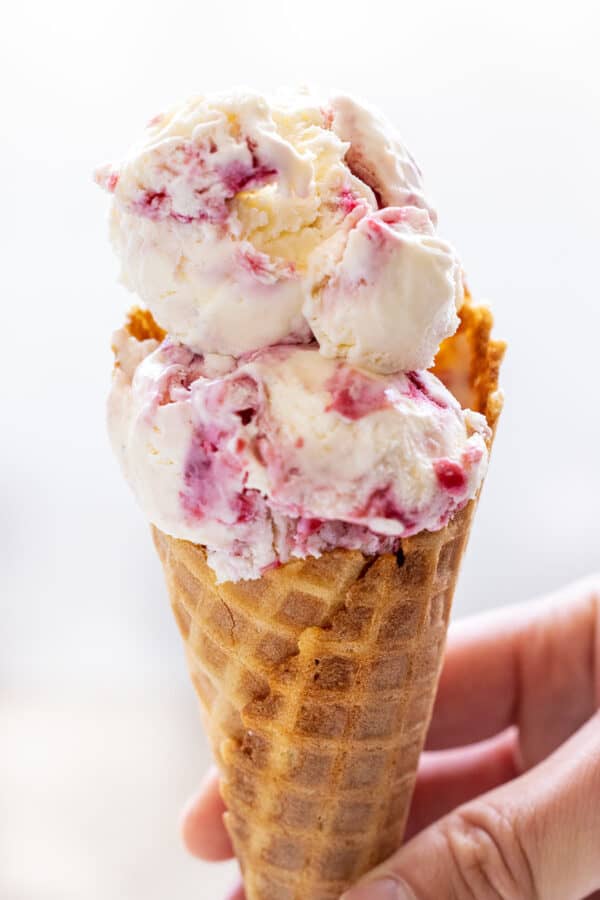 Two scoops of raspberry swirl ice cream in a waffle cone.