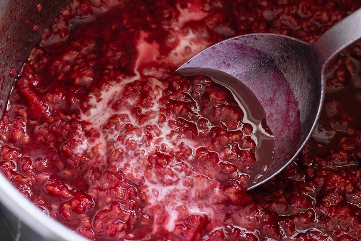 Cornstarch and water added to the saucepan filled with raspberries.