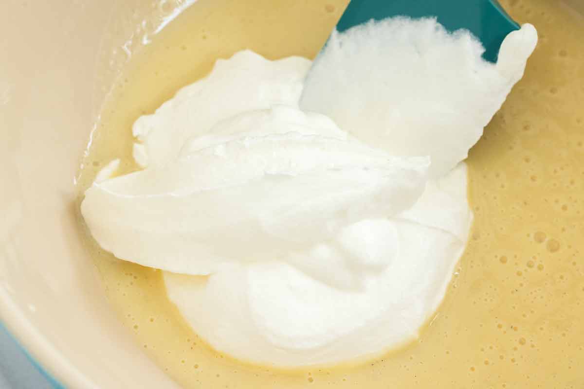 Homemade whipped cream added to a bowl of sweetened condensed milk.