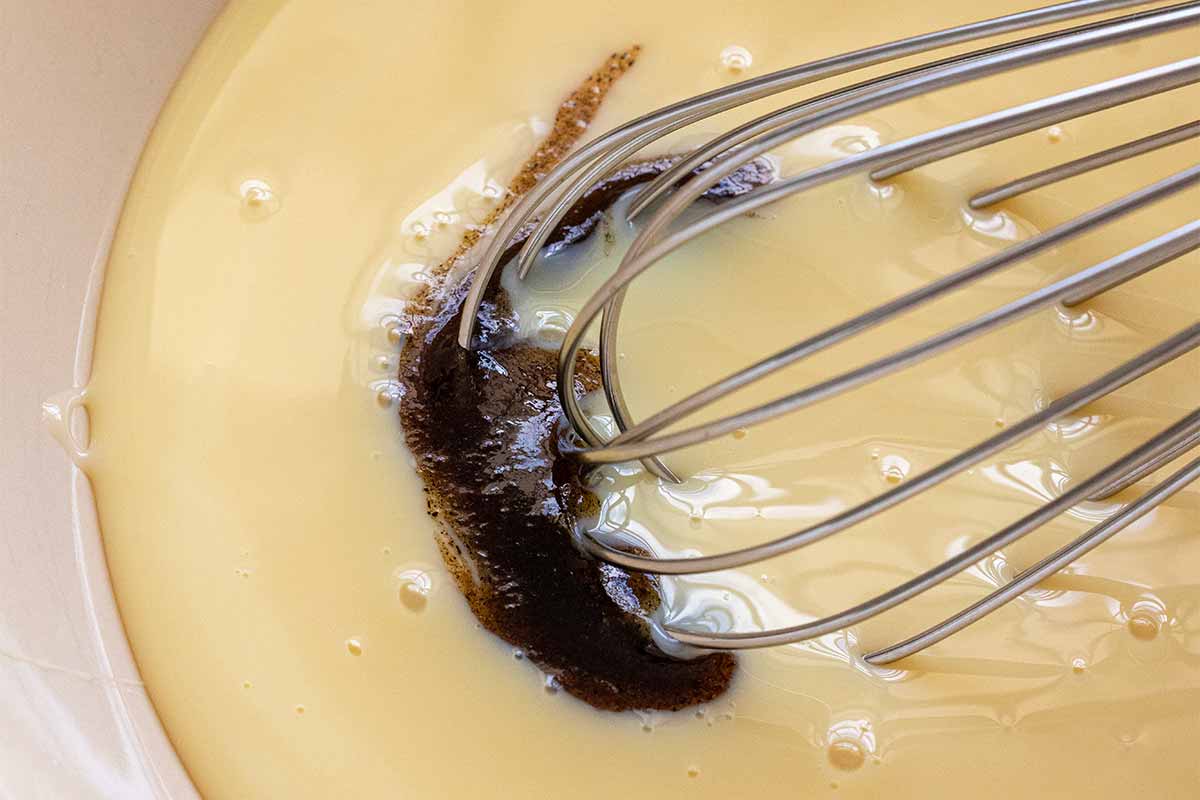 Vanilla being incorporated into a bowl of sweetened condensed milk.