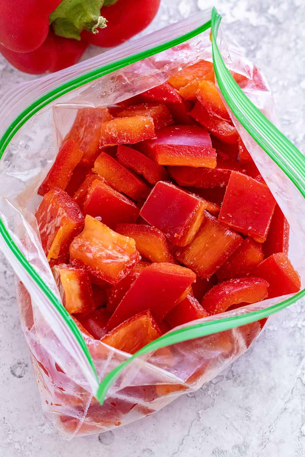 Frozen pieces of red bell pepper in a resealable plastic bag.