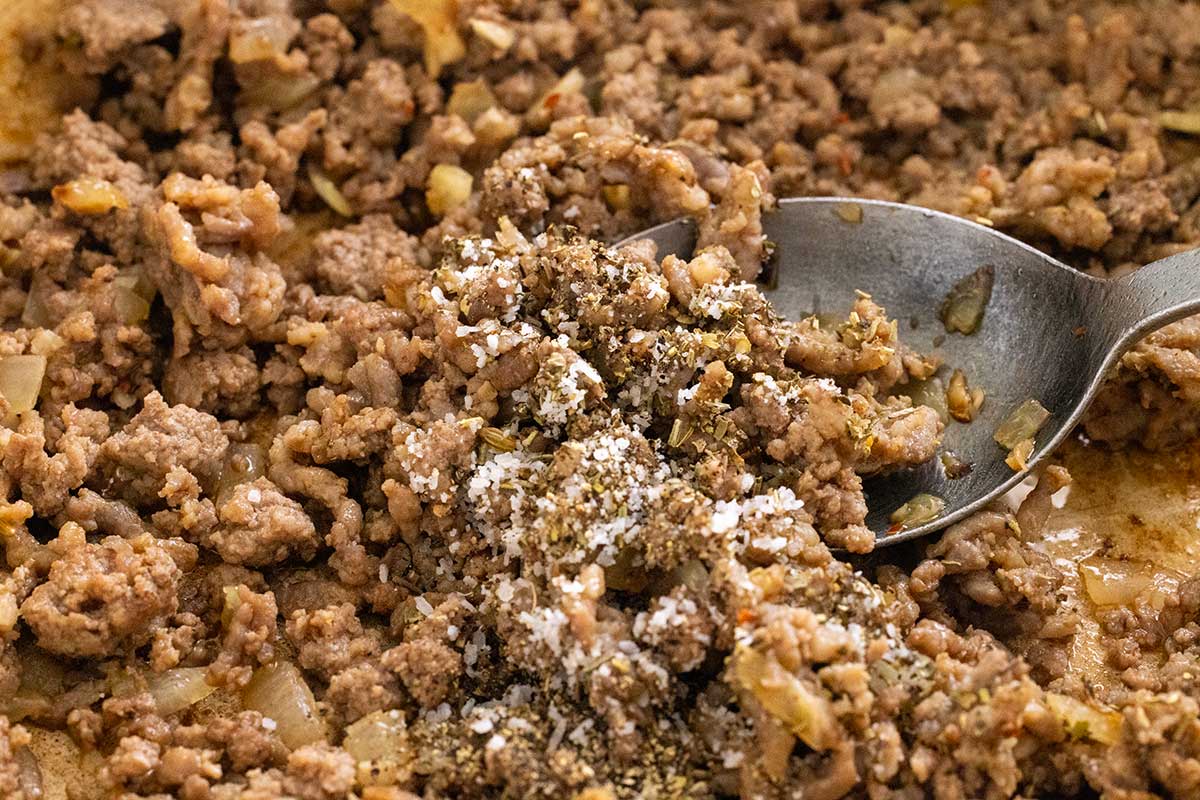 Browned ground meat and onions in a pot sprinkled with coarse salt and dried herbs.