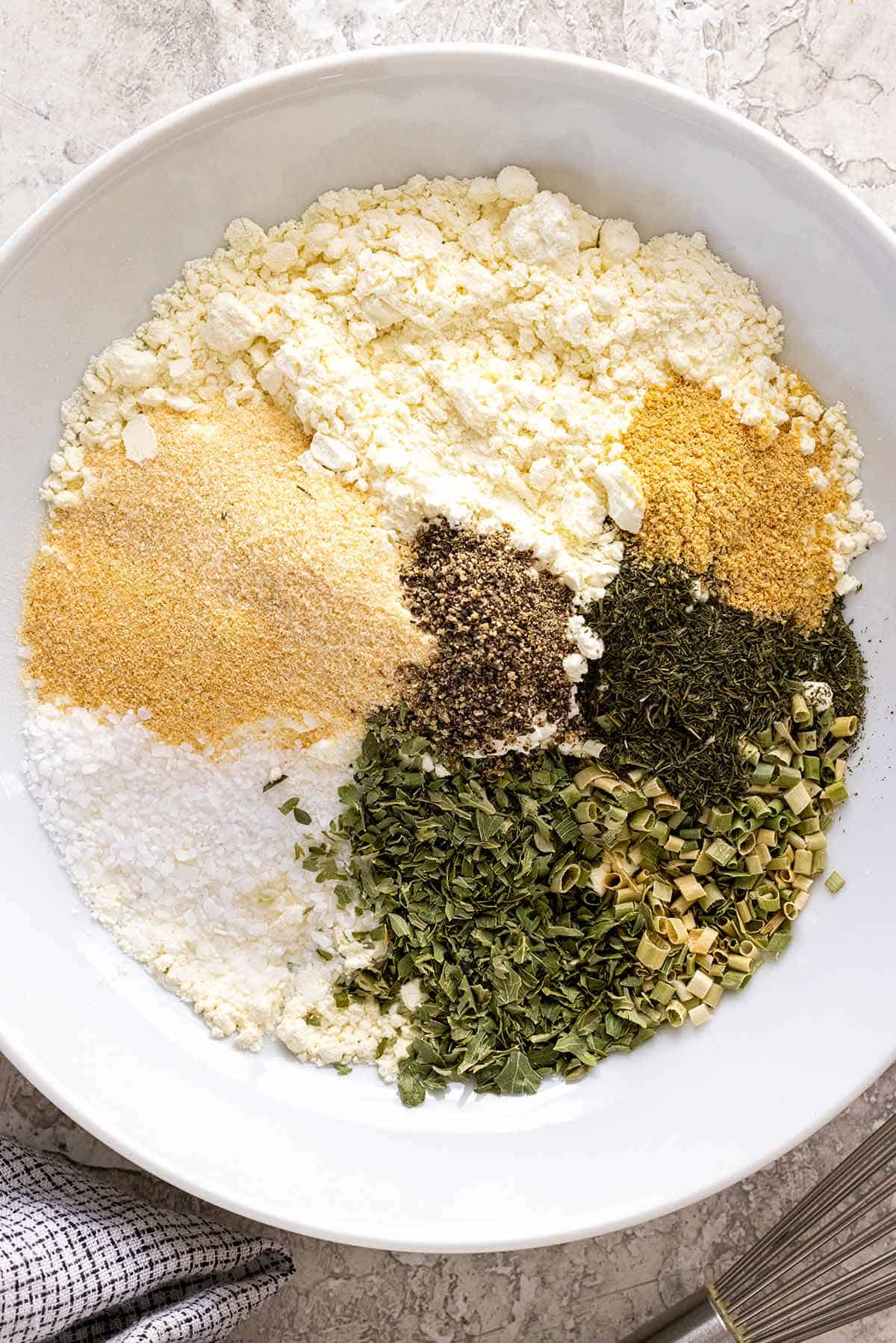 Several unmixed dried spices and powders in a large bowl.