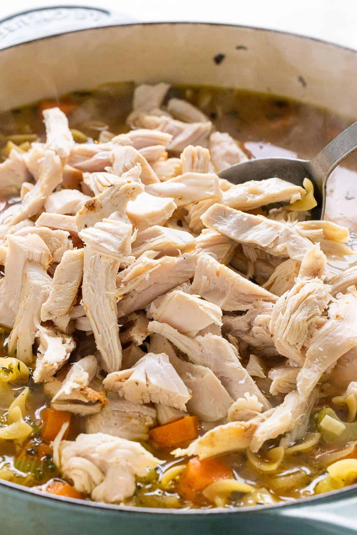 Shredded turkey pieces added to a pot of soup.