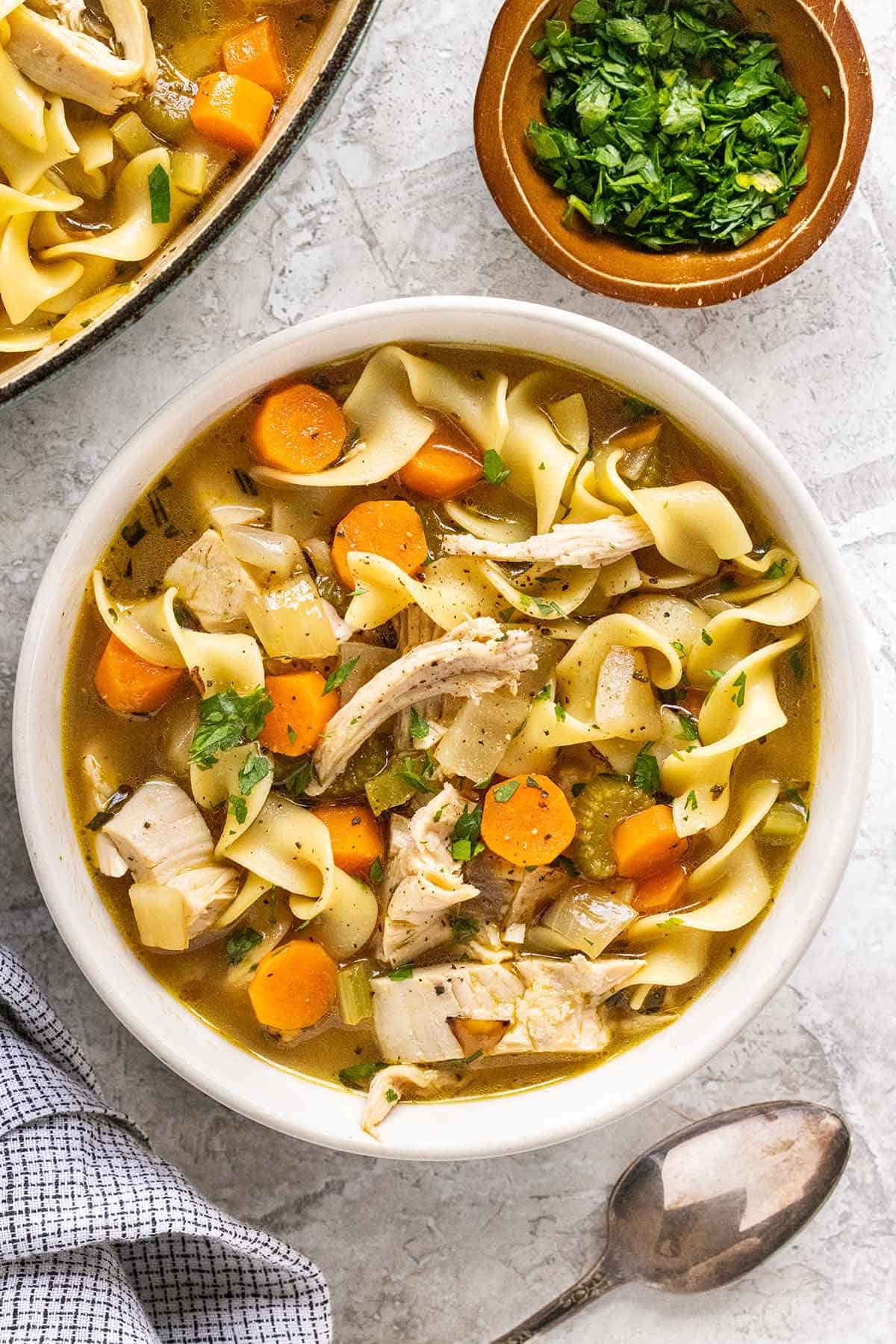Homemade turkey and noodle soup served in a white bowl.