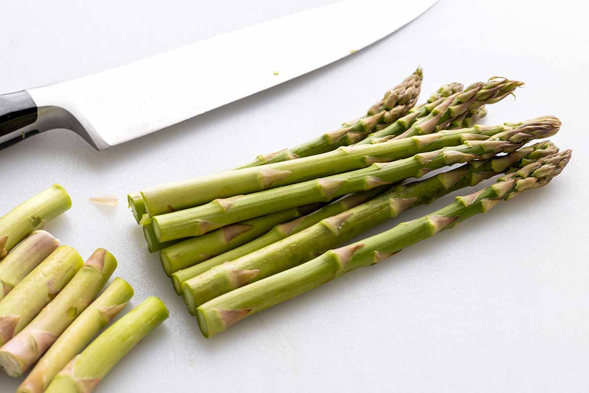 Person cutting the ends of a bundle of asparagus.