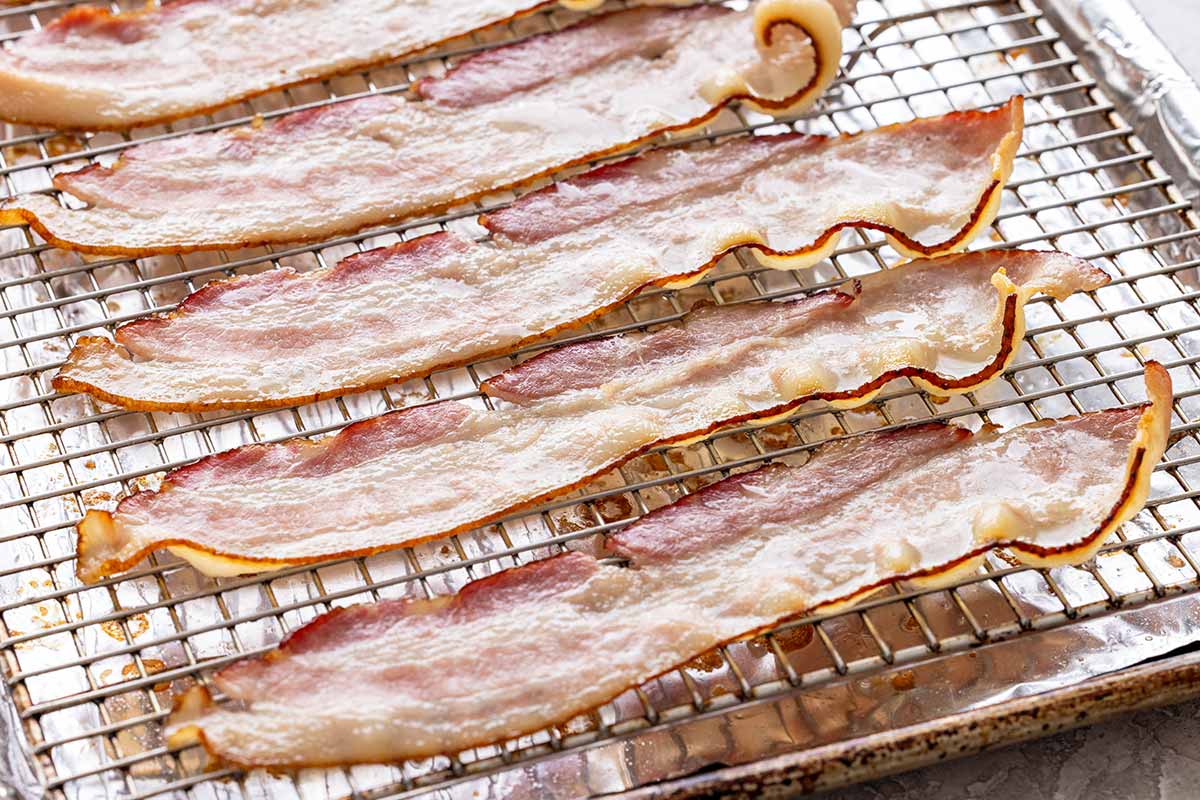 Slices of bacon roasting on a wire rack.