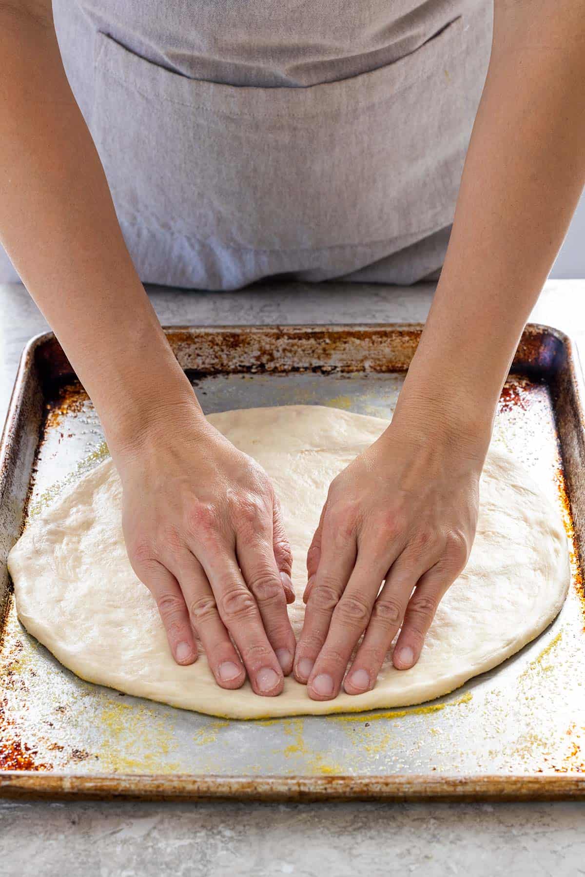 Jessica using her fingertips to shape the dough into a circle.