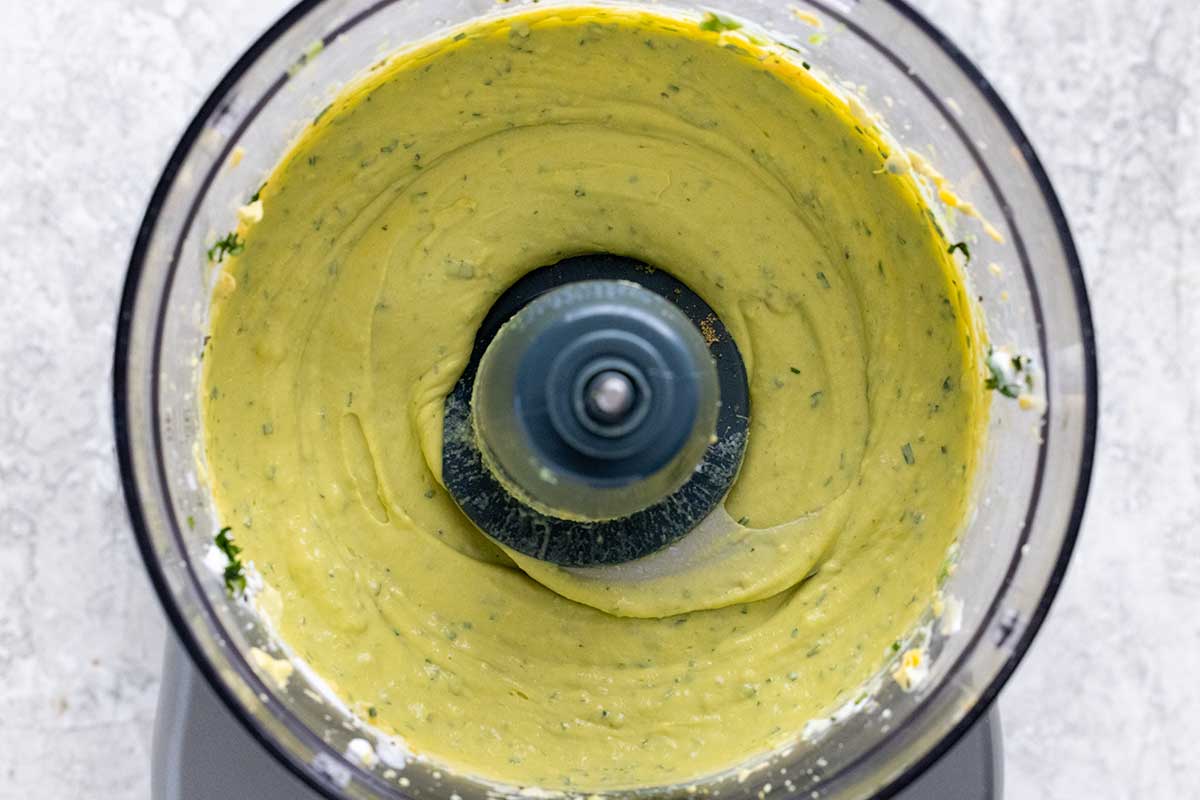 Green egg yolk puree inside the cup of a food processor.