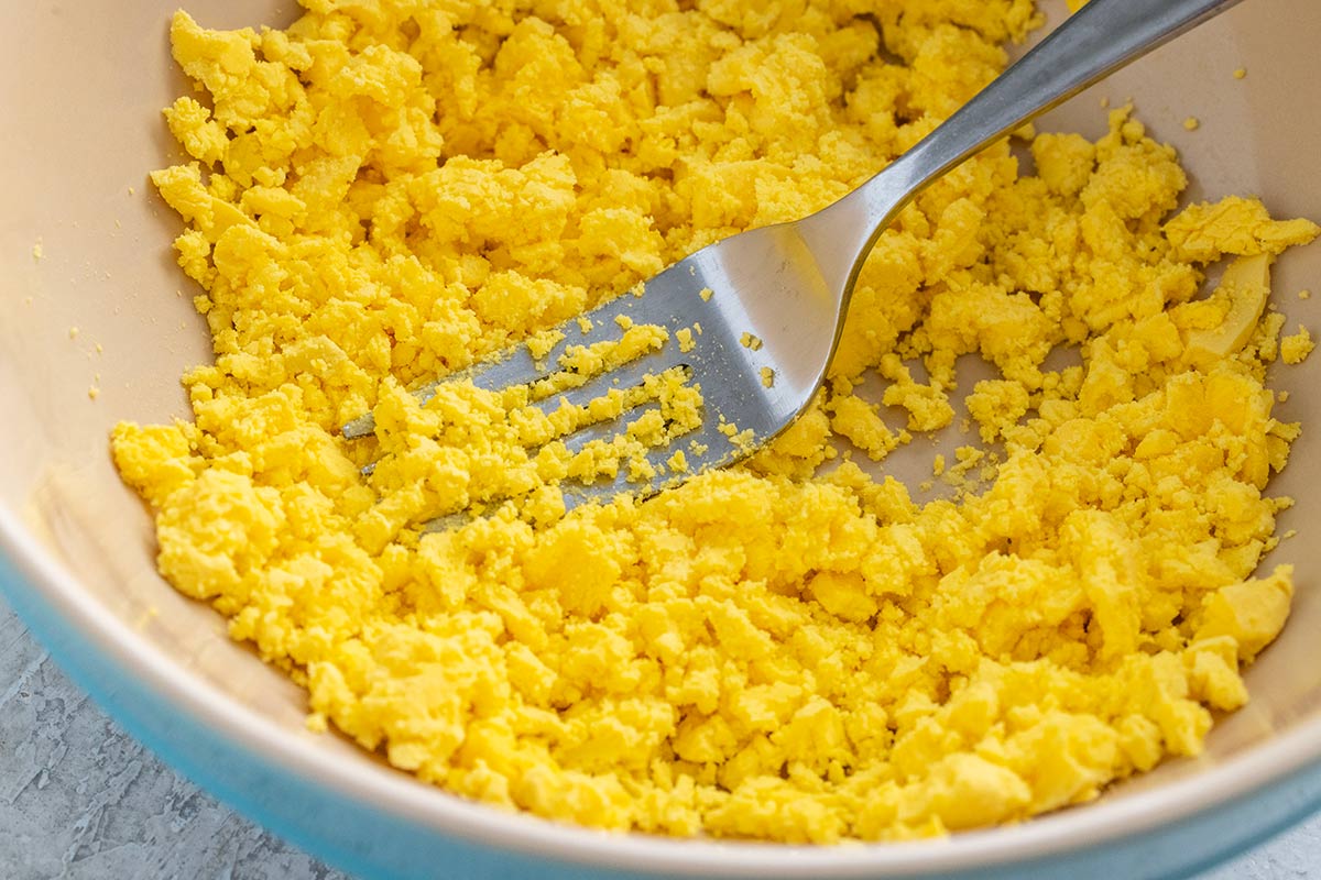 Bowl of egg yolks that have been mashed into crumbles with a fork.