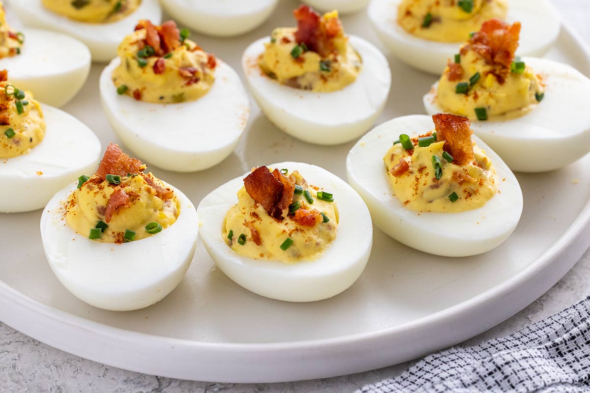 Delicious bacon deviled eggs garnished with paprika and chives on top.