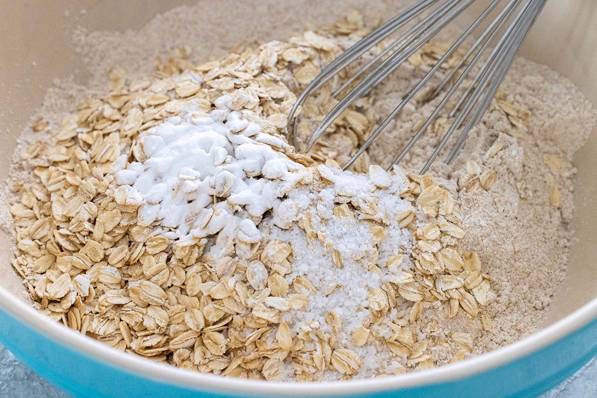 Rolled oats, baking soda, salt, and whole wheat flour in a large blue bowl.