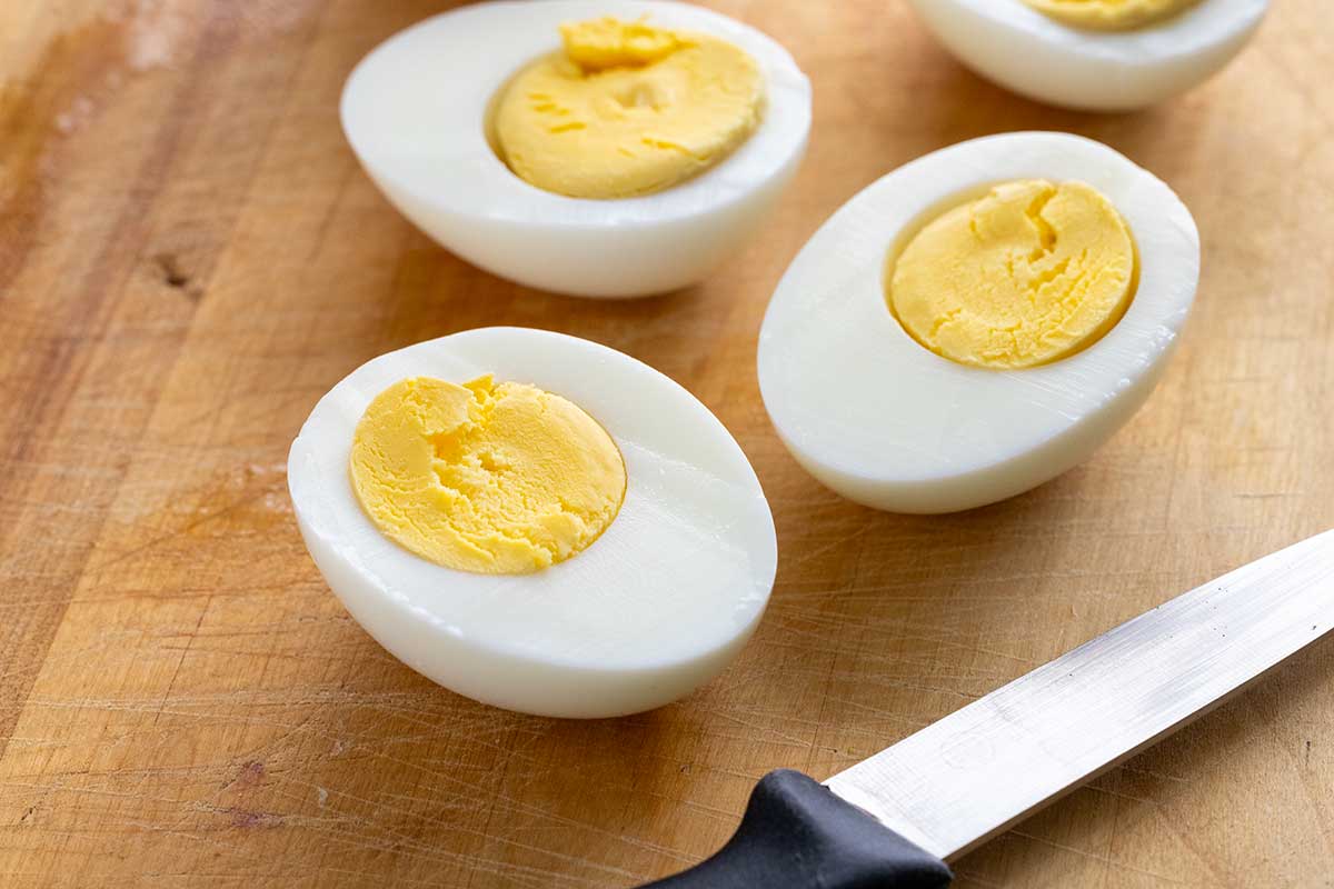 Hard-boiled eggs cut in half on a cutting board.