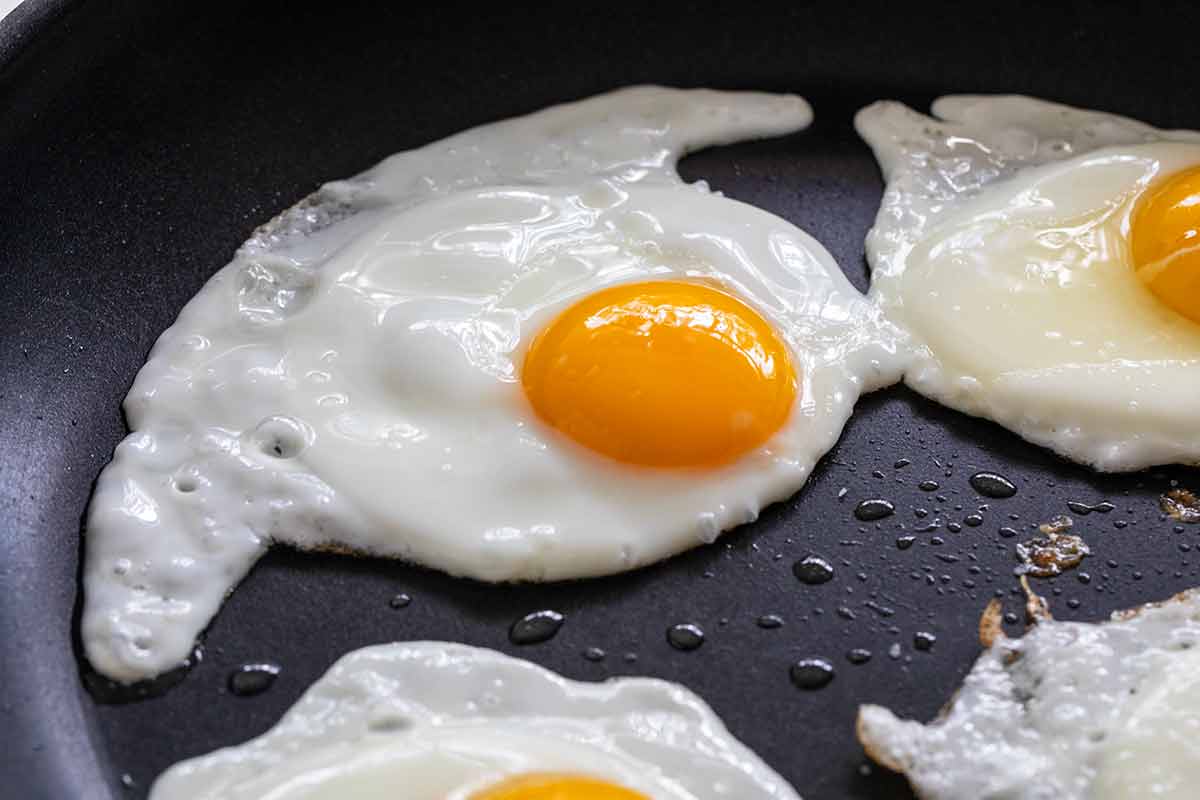 Sunny side eggs frying in a nonstick skillet.