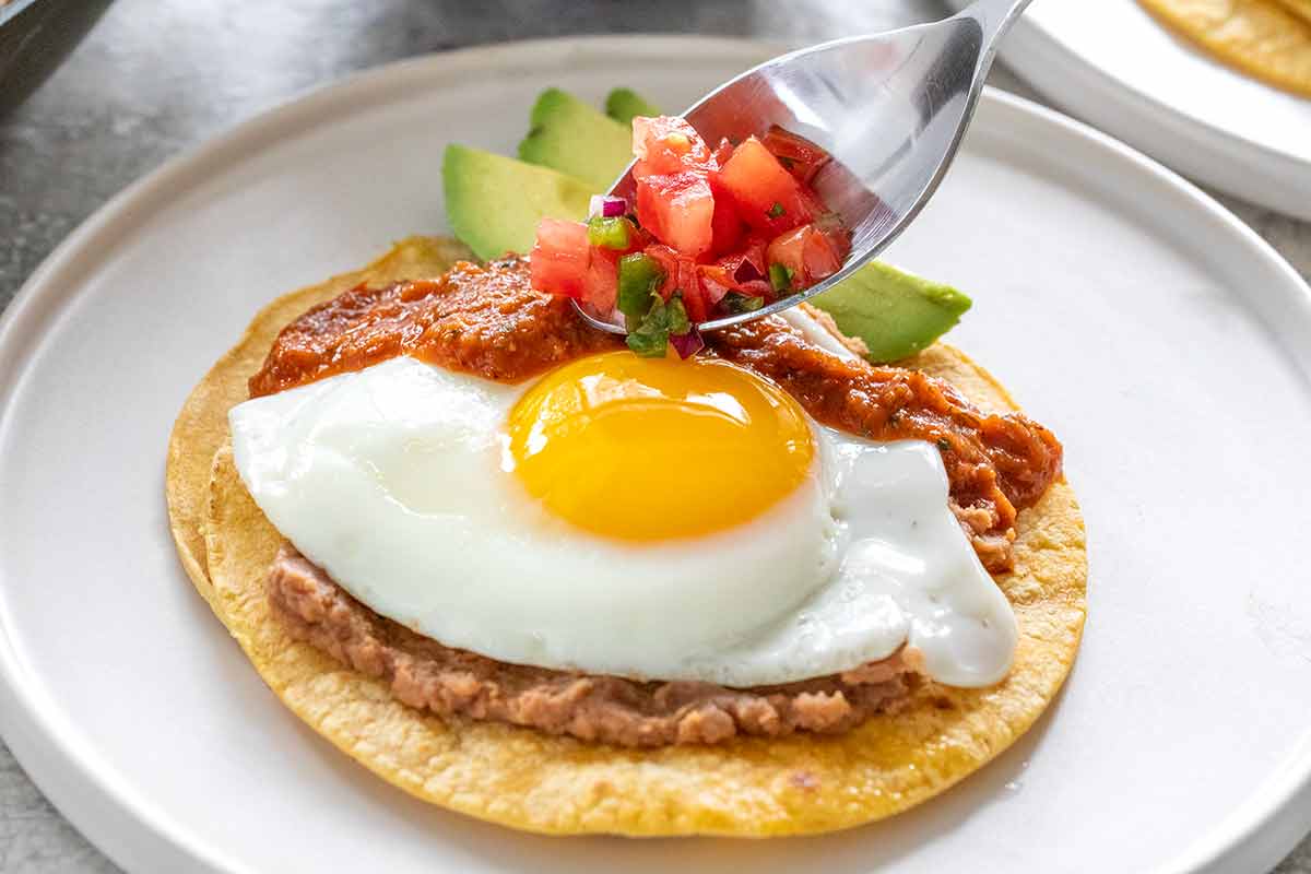 Adding pico de gallo on top of the huevos rancheros.