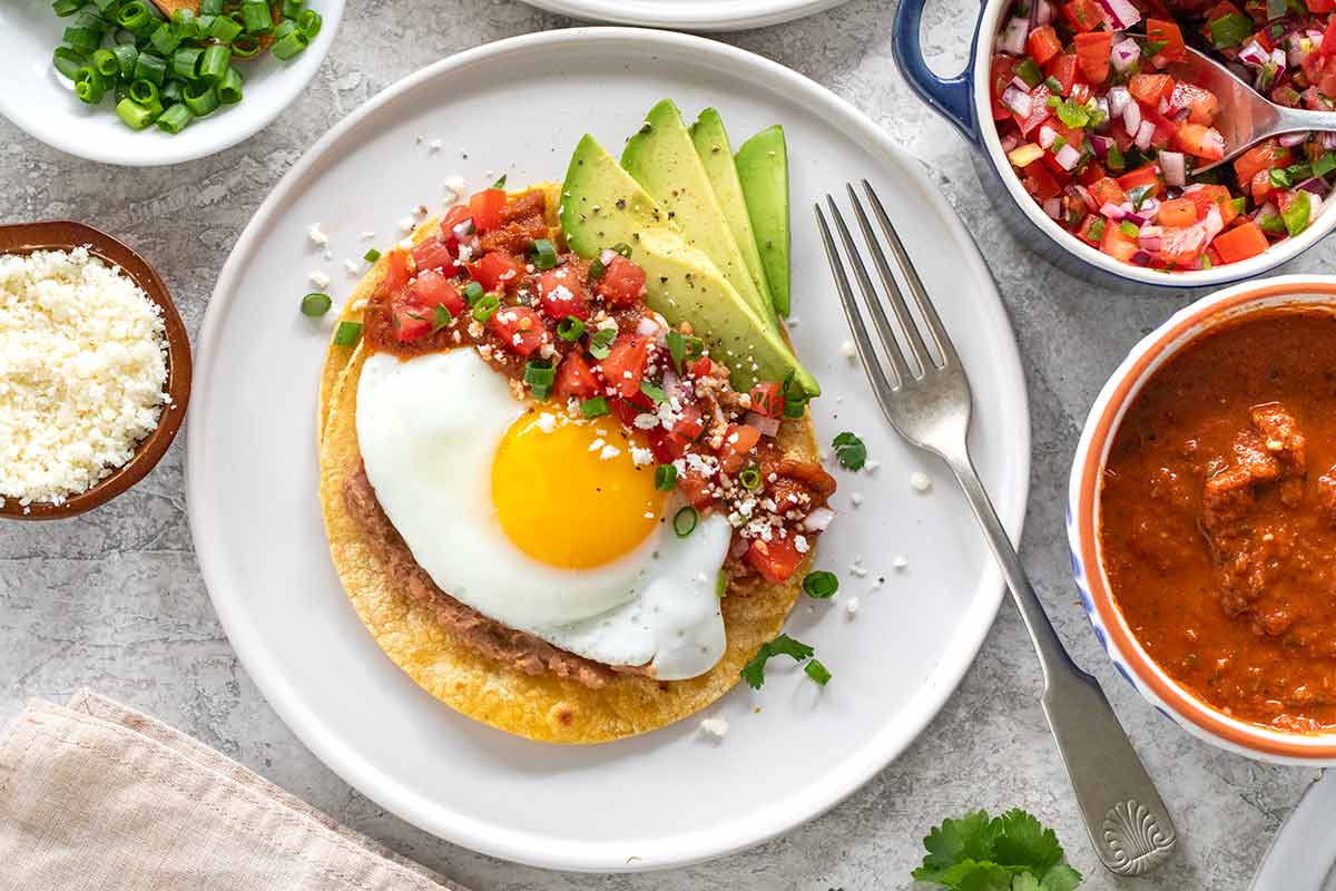 Huevos rancheros served with slices of avocado and pico de gallo.