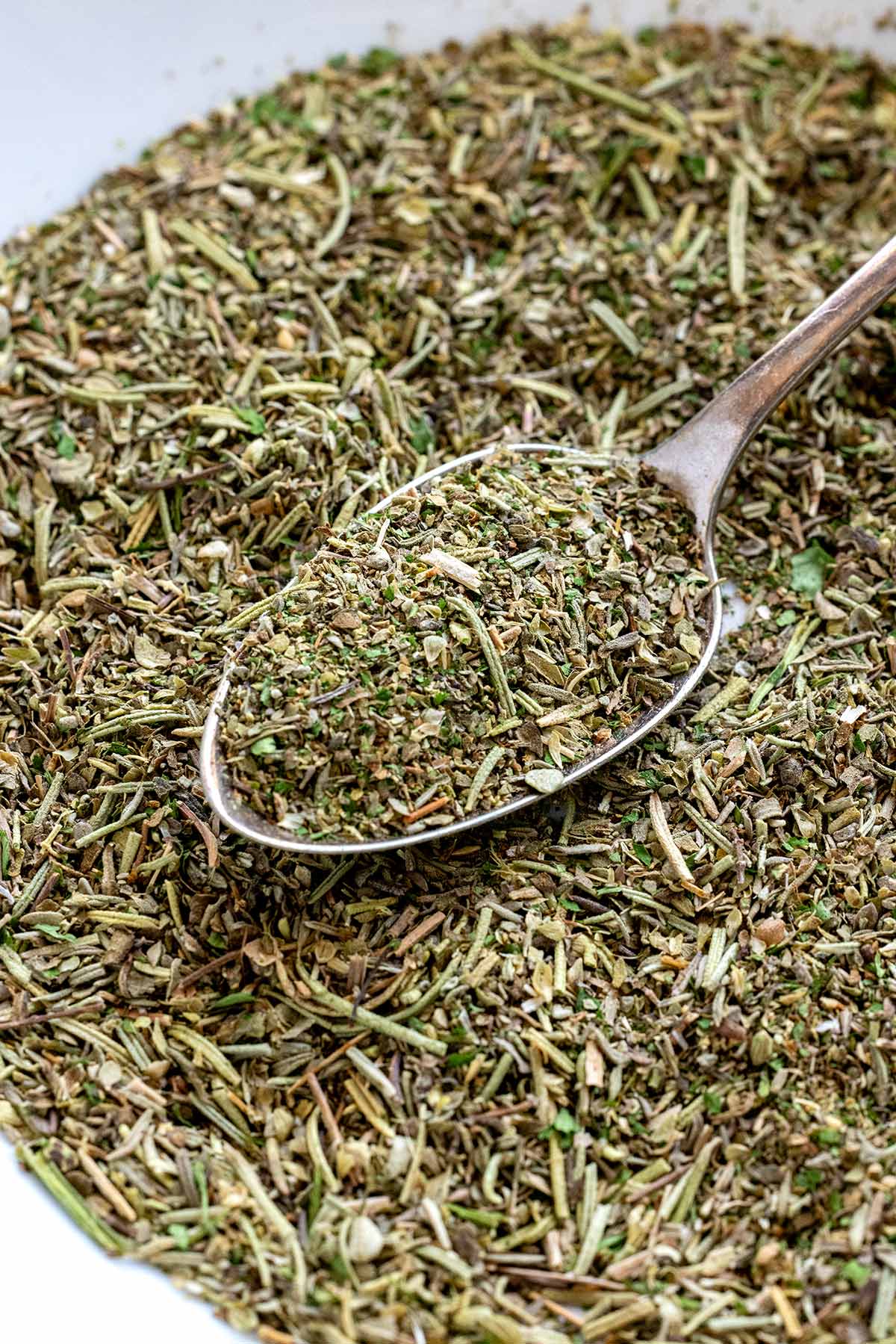 Homemade Italian seasoning in a bowl with a spoon.