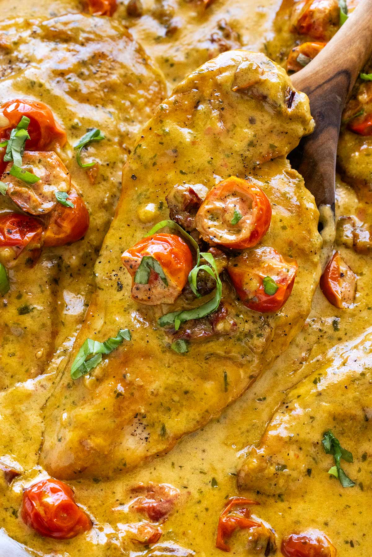 Piece of chicken breast smother in a creamy pesto sauce.