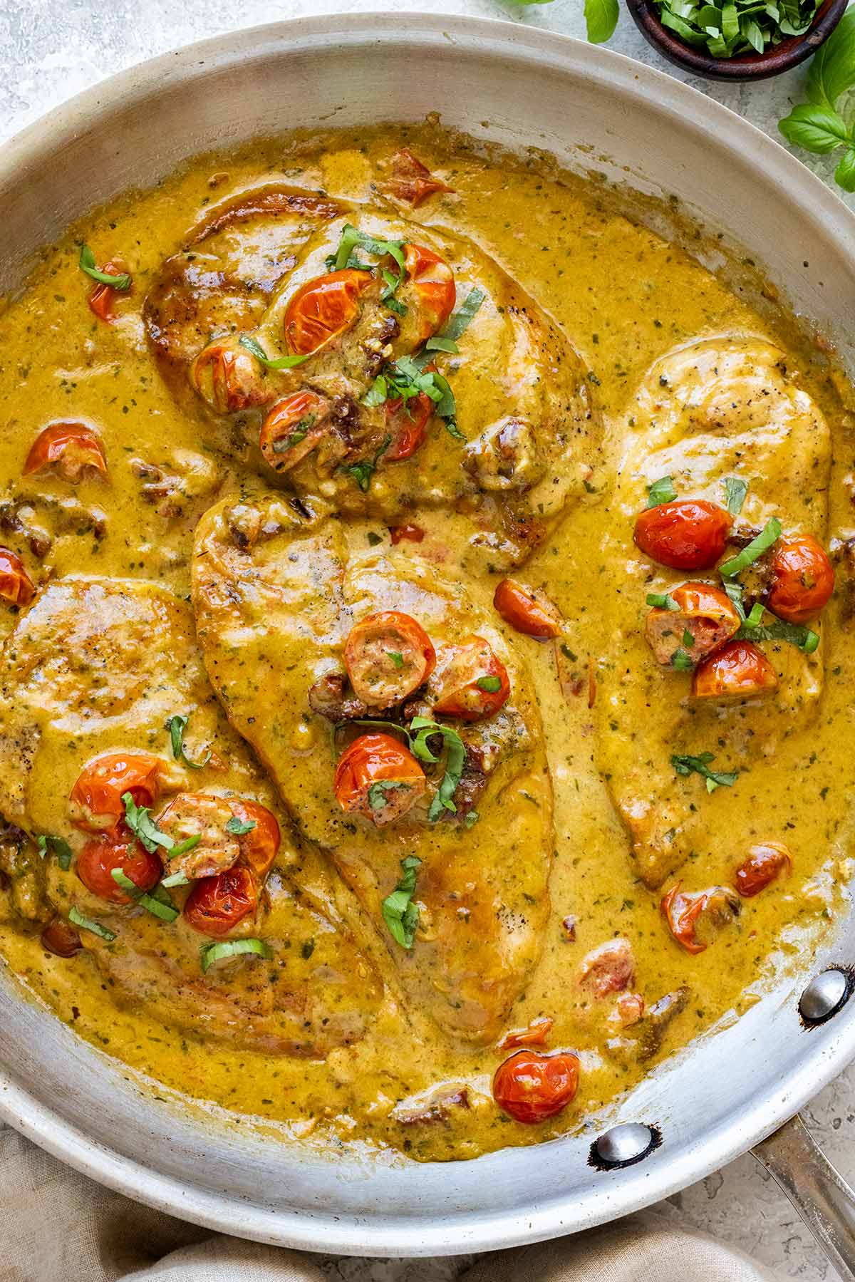 Creamy pesto chicken in a large stainless pan.