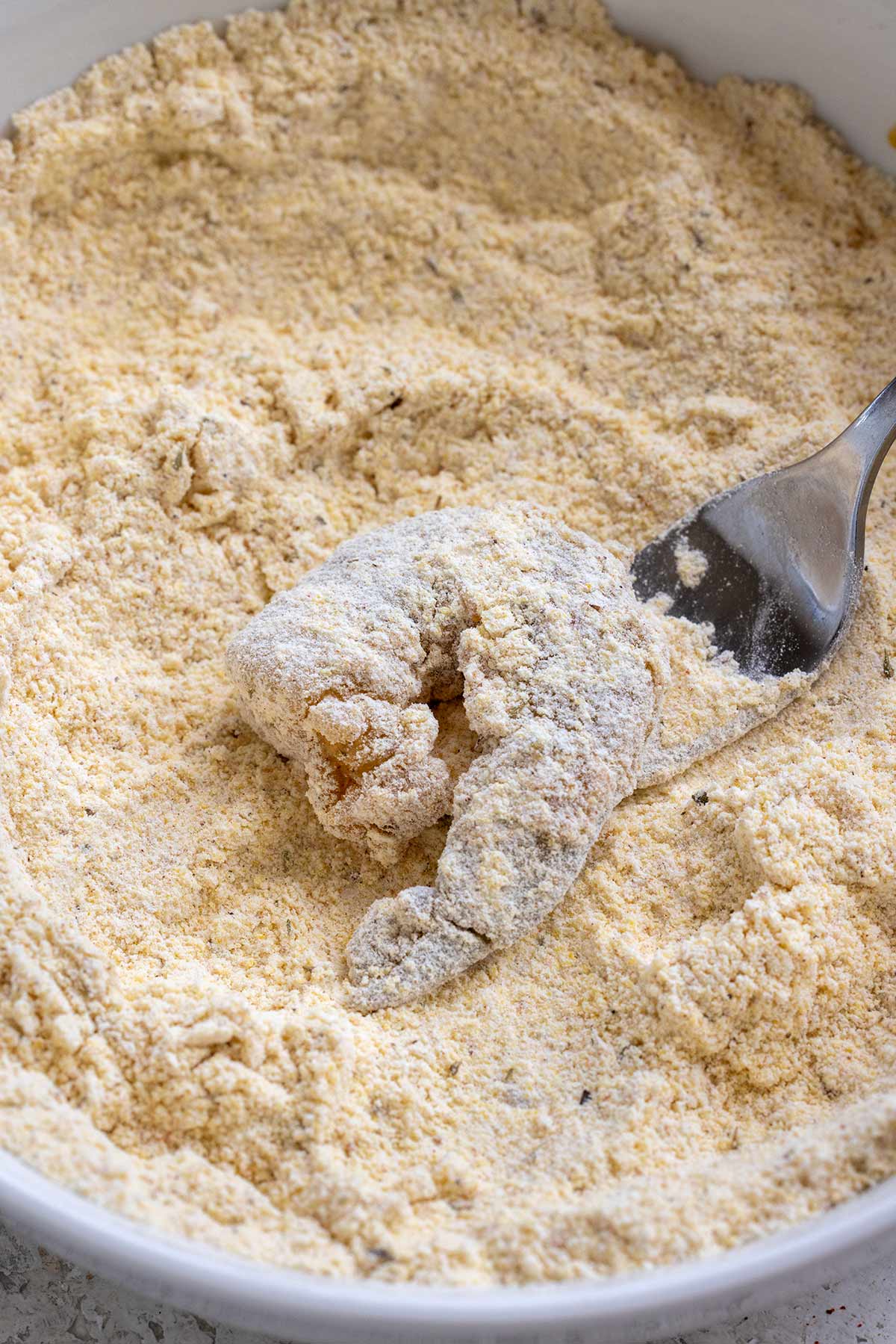 A shrimp inside a bowl of flour coating.