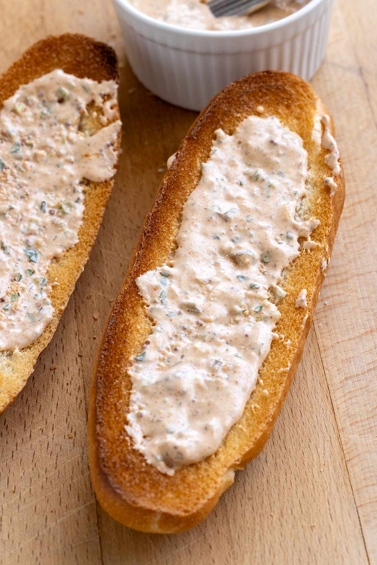 Loaf of toasted French bread with remoulade sauce spread on it.