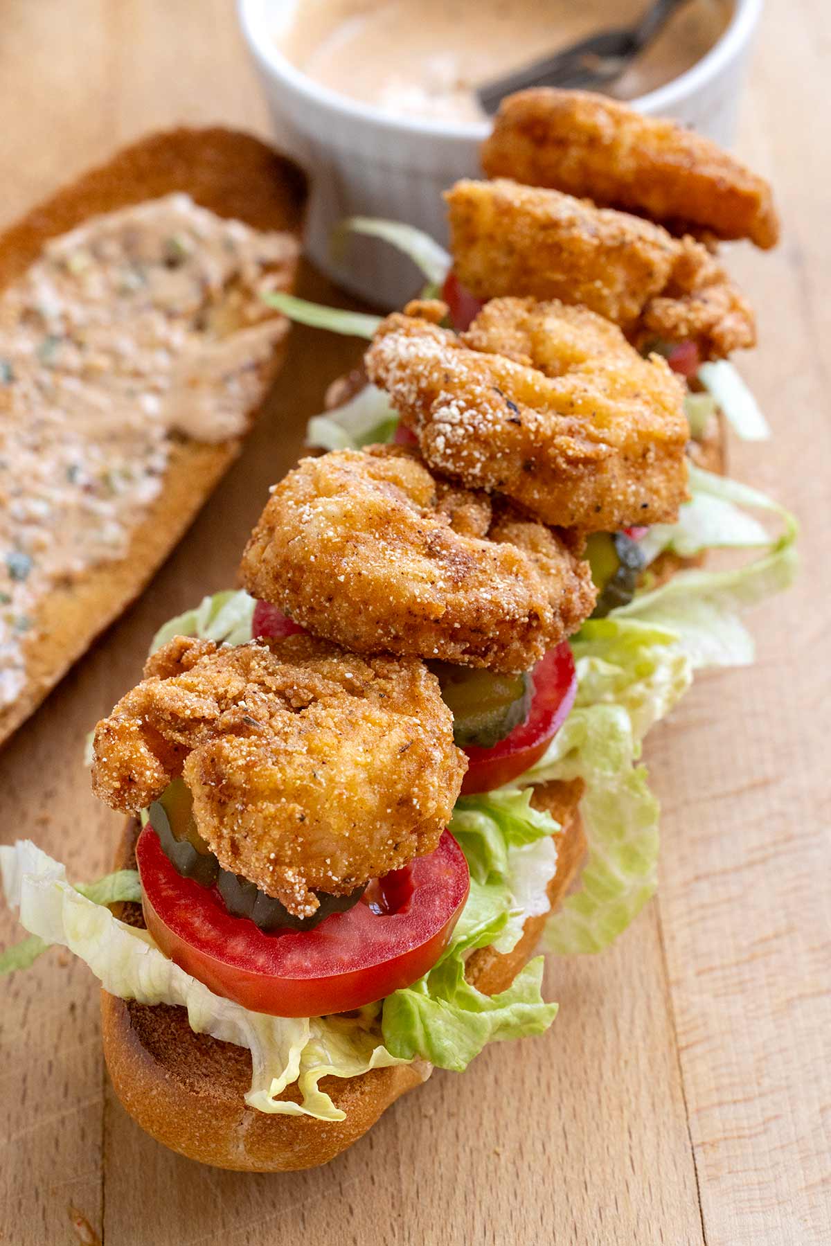 Fried shrimp sandwich with lettuce, tomato, and pickles.
