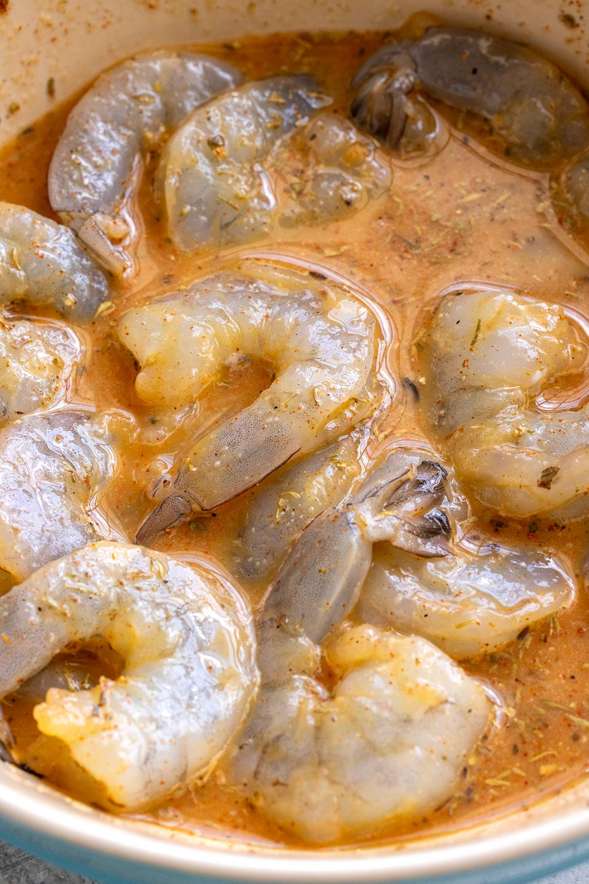 Shrimp marinating in a bowl of spices and hot sauce.