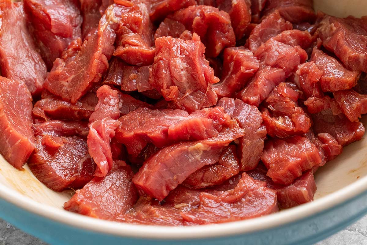 Pieces of steak marinating in a bowl.