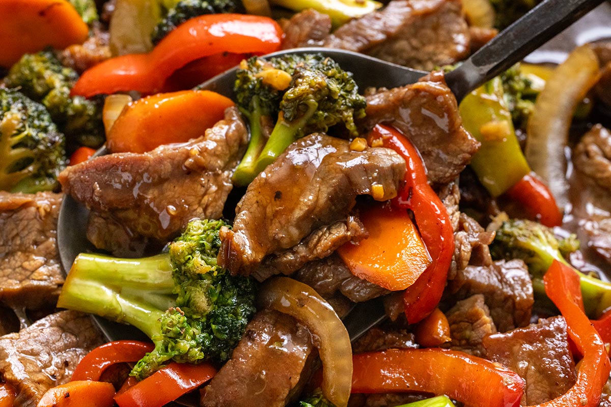 Beef and vegetables being tossed in a stir fry sauce.
