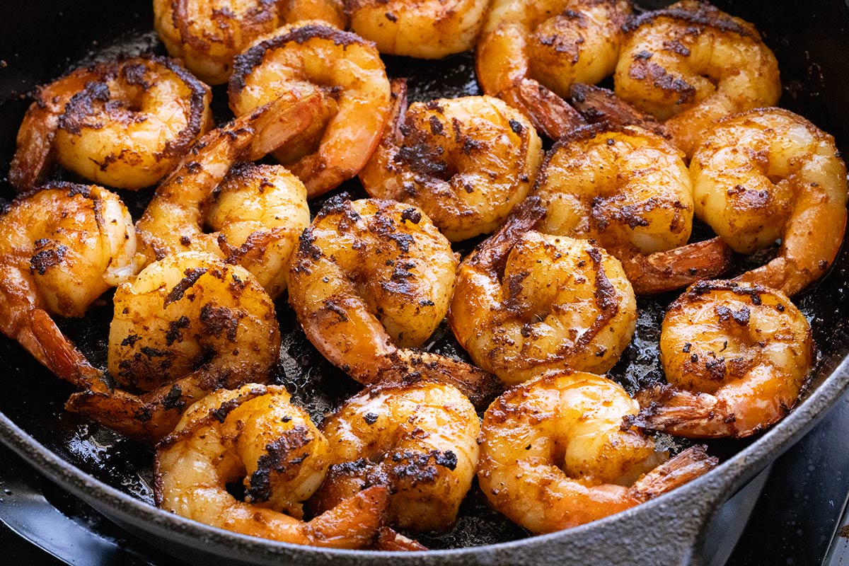 Several shrimp cooking in a cast iron pan.