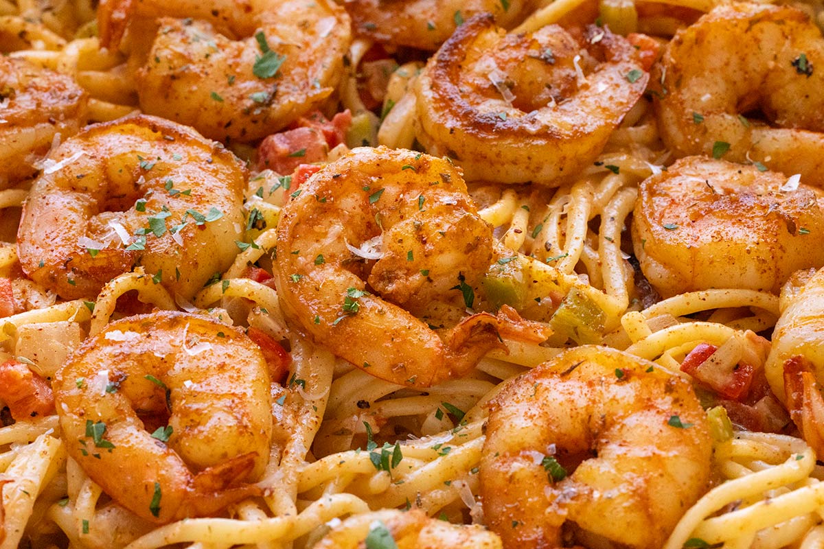 Spicy seasoned shrimp laying on top of spaghetti noodles.