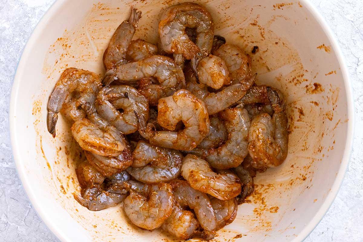Shrimp in a bowl that have been tossed in Cajun seasoning.