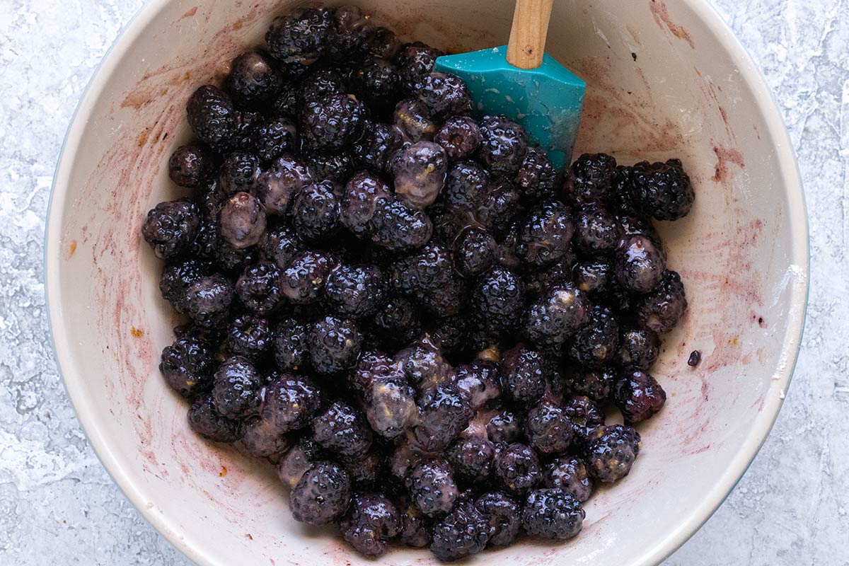 Blackberries in a bowl being mixed with sugar and cornstarch.