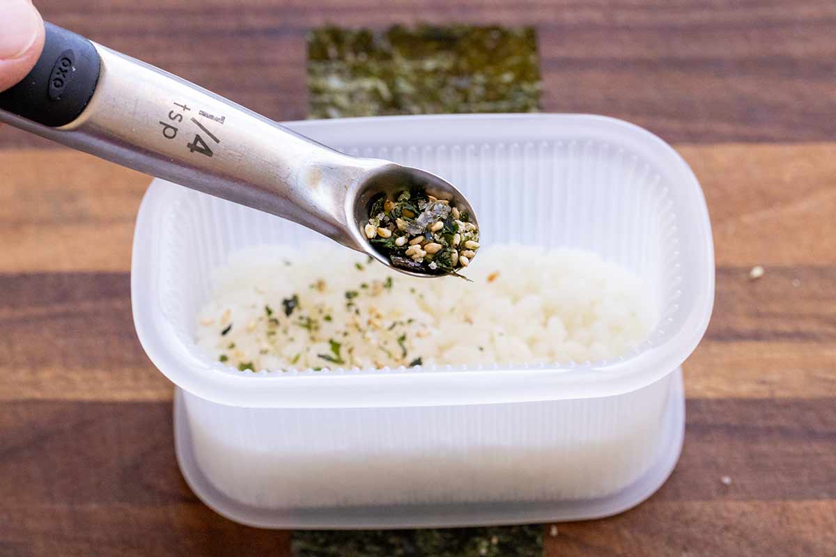 Furikake being added to a musubi press.