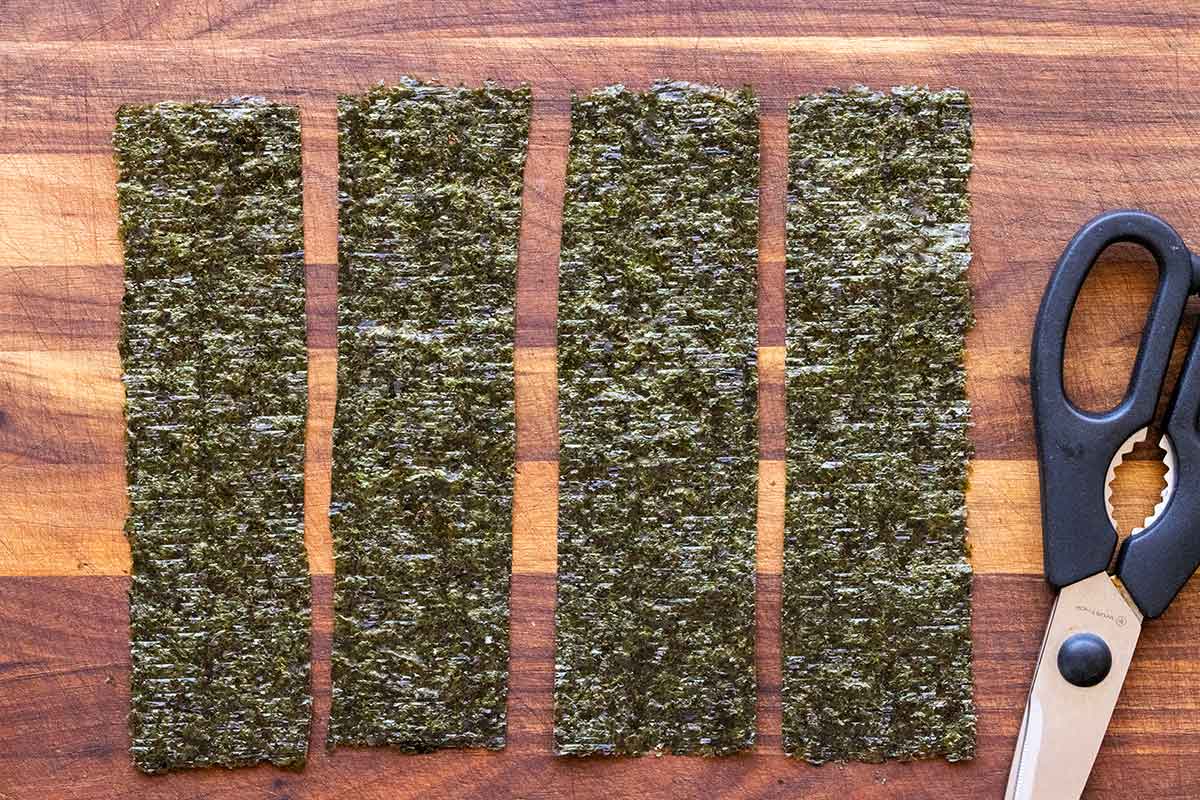 Four pieces of nori cut into strips and placed on a cutting board.
