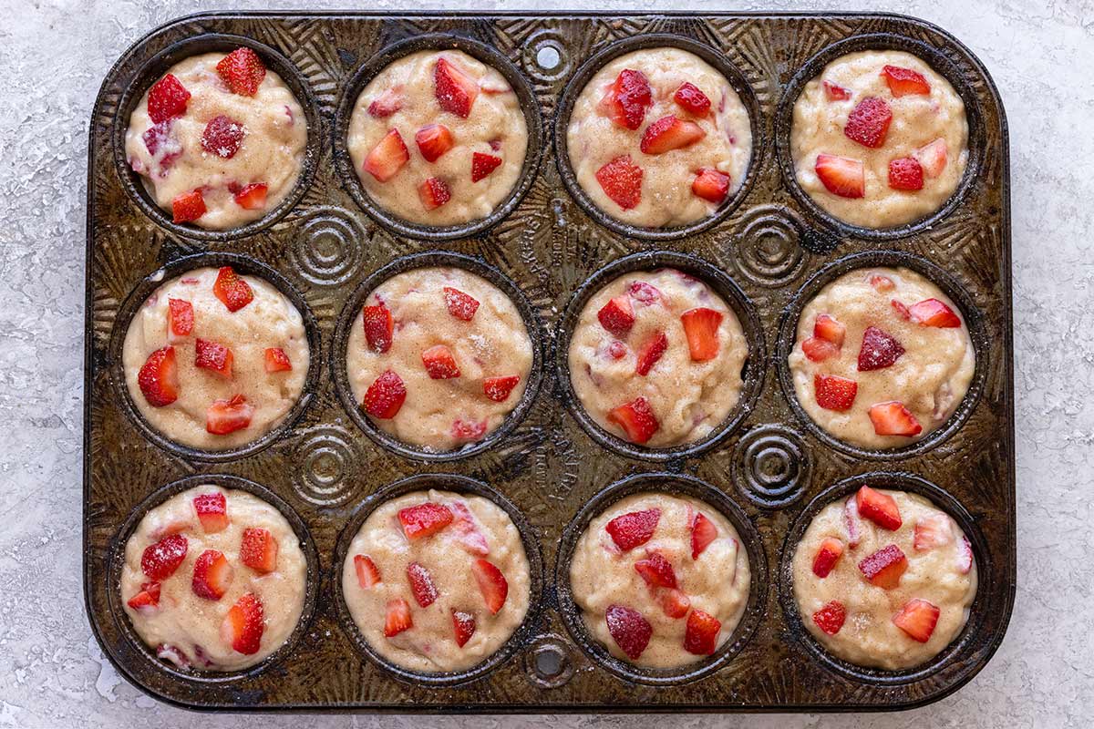 Strawberry muffin batter portioned into a 12 cup muffin tin.