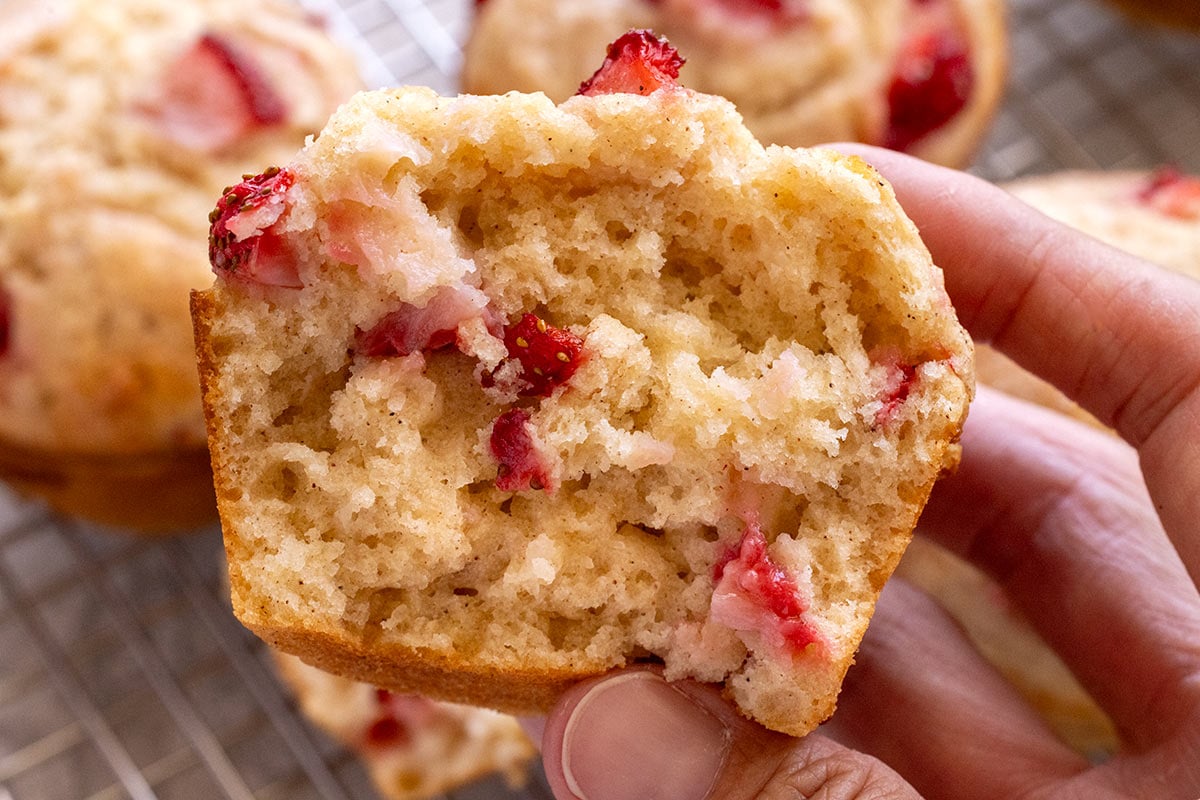 Muffin split open showing strawberry pieces inside.