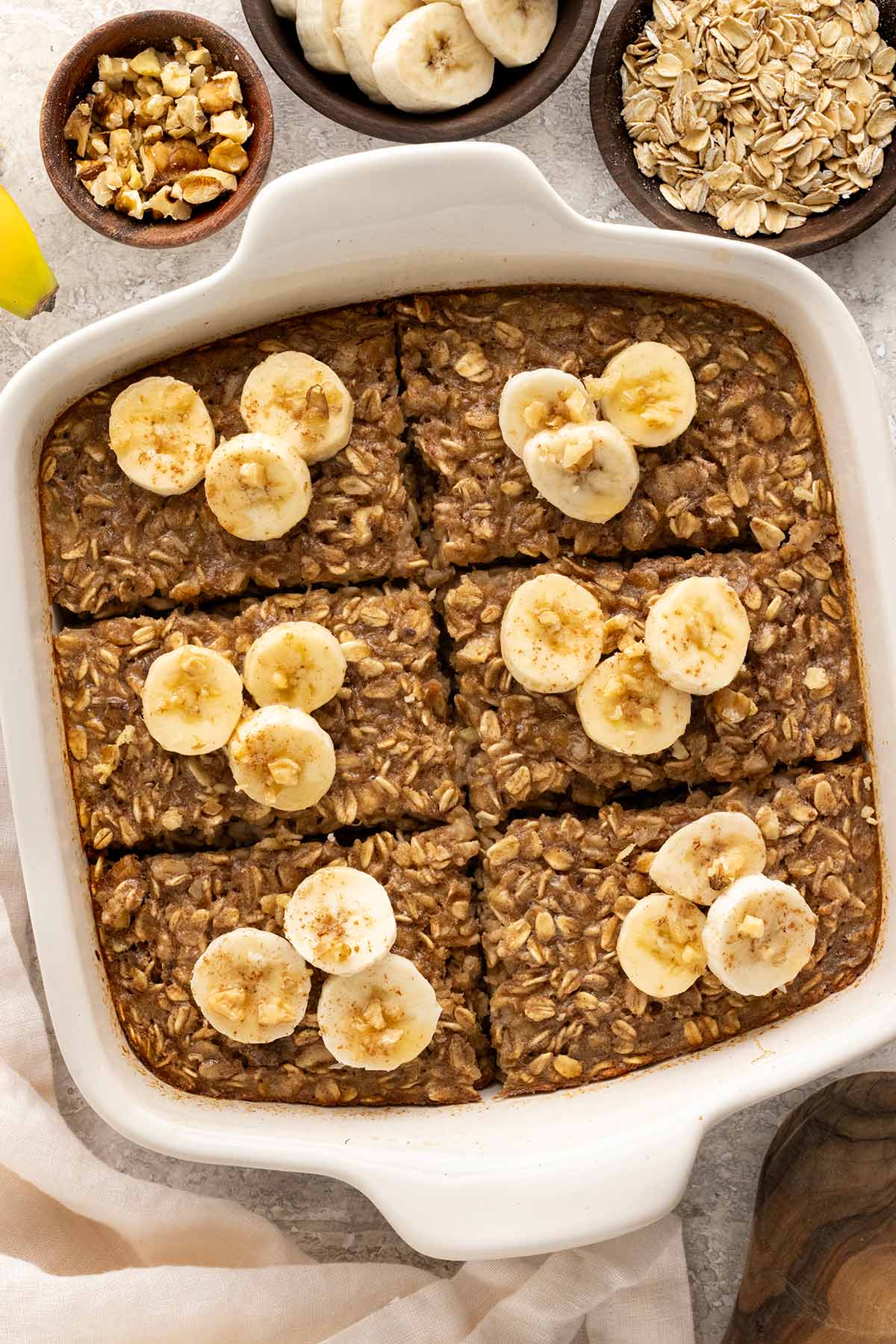 Banana baked oatmeal in a white baking dish with sliced bananas on top.