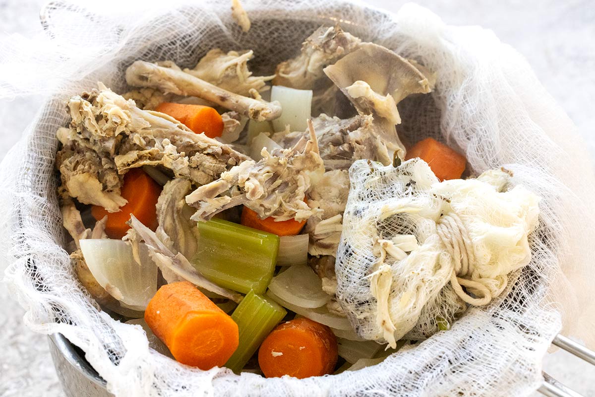 Chicken and vegetable pieces remaining after straining liquid through a cheesecloth.