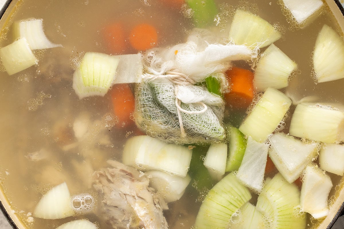 Mirepoix and sachet added to a pot of chicken stock.