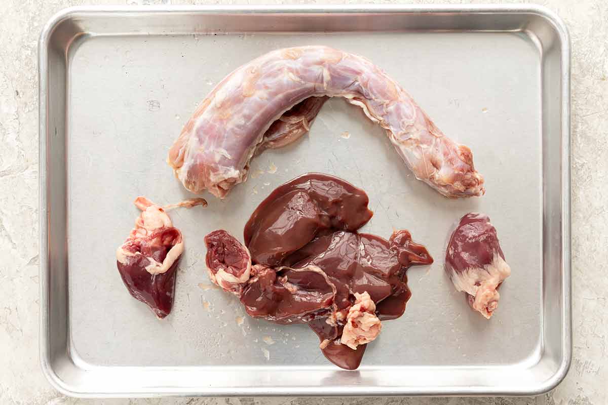 Turkey giblets and neck placed on a silver sheet pan.