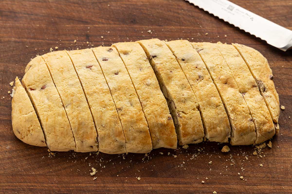 Loaf of biscotti on a cutting board with slices cut into it.