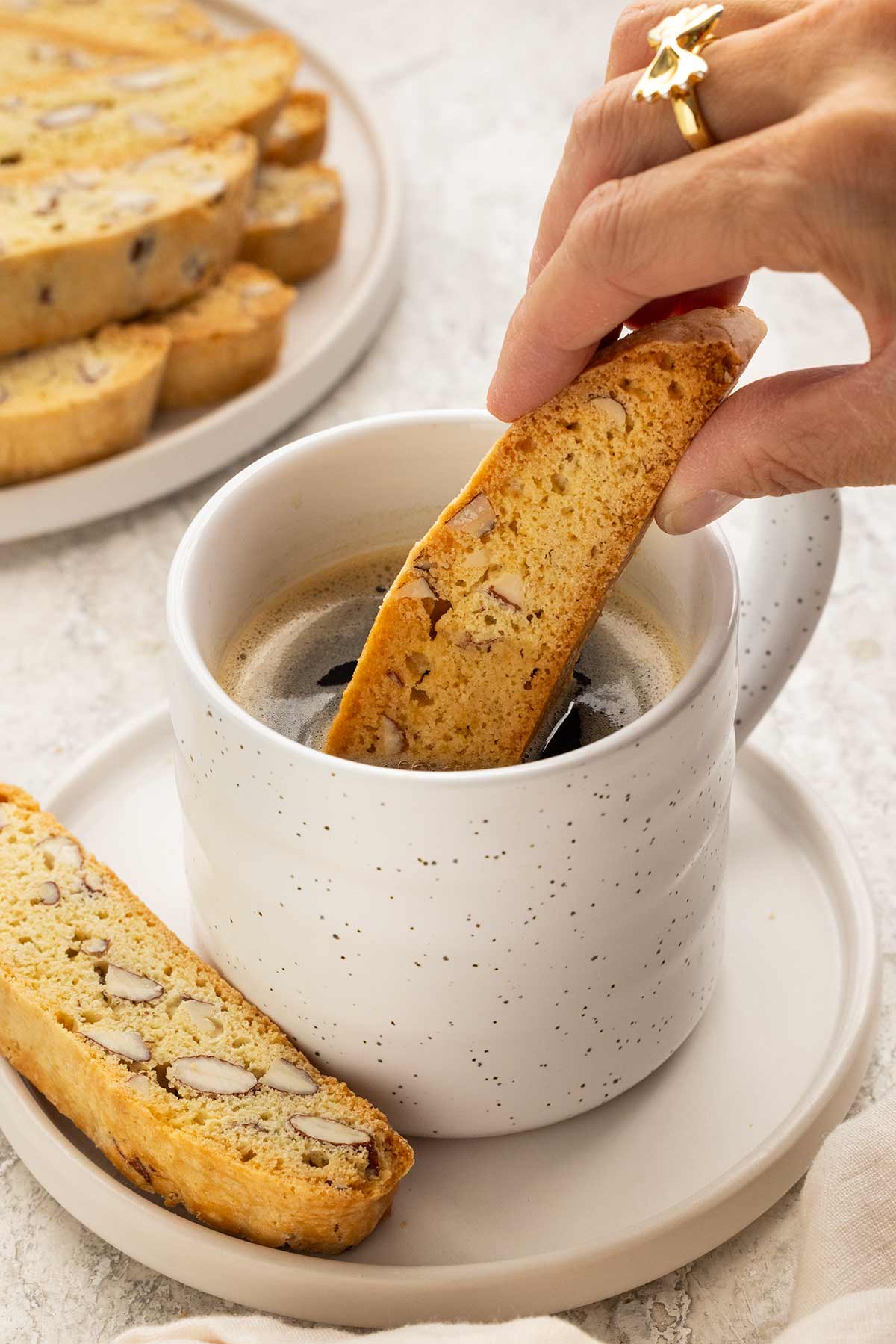 Person dipping a biscotti cookie into a cup of coffee.