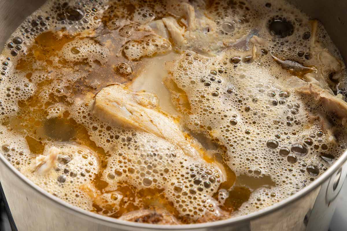 Turkey bones and meat simmering in a large stockpot.