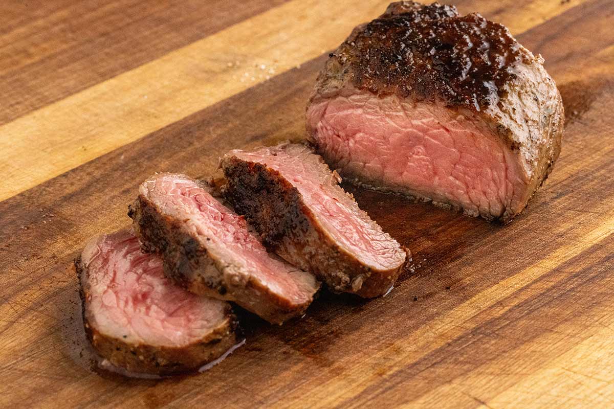 Top sirloin steak on a cutting board cut into slices.