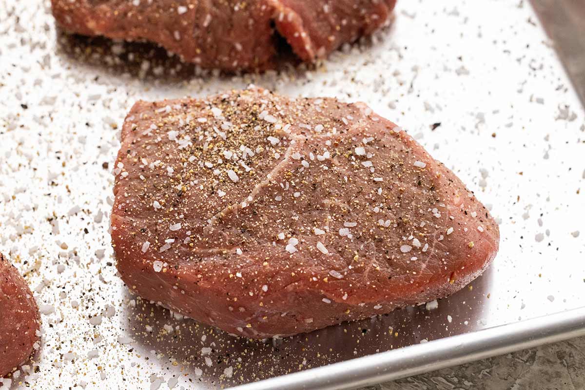 Steak fillet seasoned with salt and pepper and placed on a sheet pan.